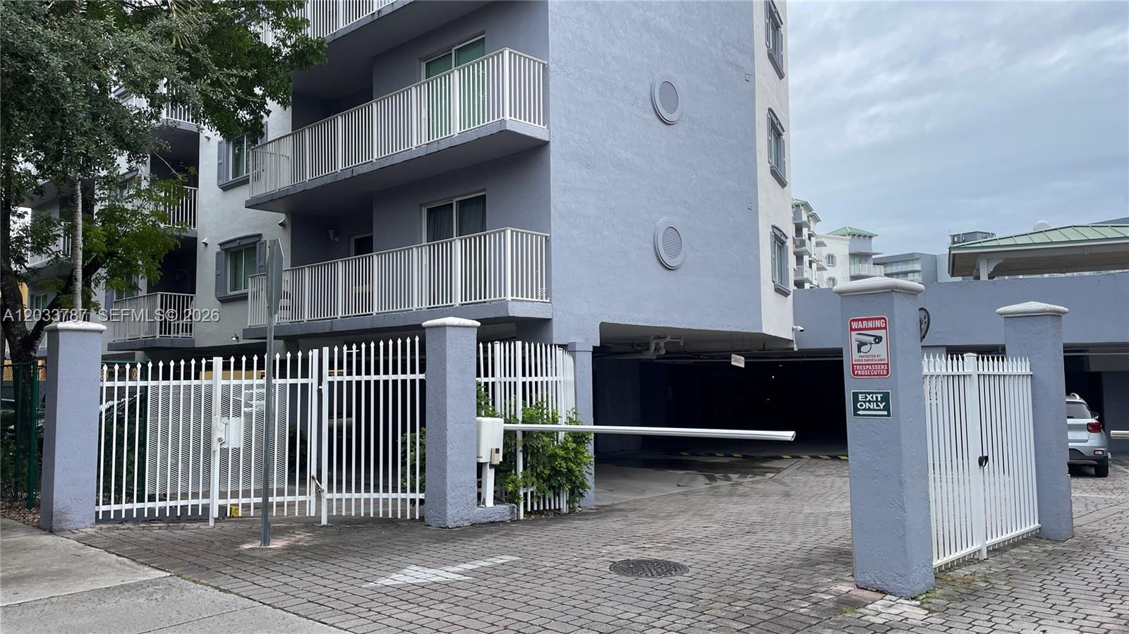 The exterior view shows a multi-story apartment building with a gated parking garage entrance — 2475 NW 16th St Rd # 309, Miami FL 33125, MIAMI, FL