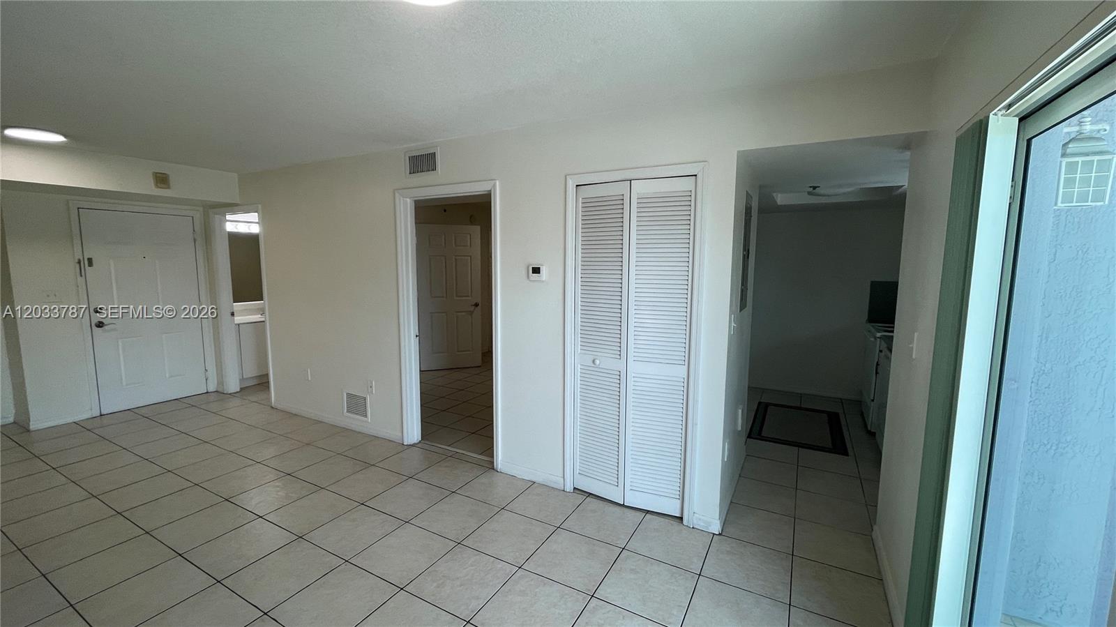 A tiled living area features a white front door, a closet, and two interior doorways — 2475 NW 16th St Rd # 309, Miami FL 33125, MIAMI, FL