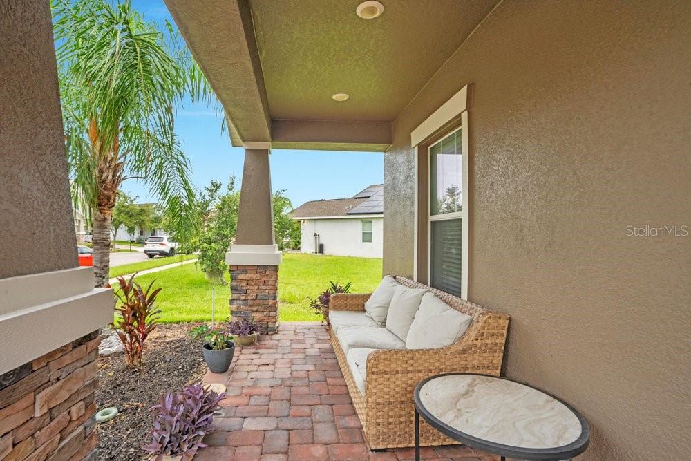 A covered front porch features brick pavers, a wicker sofa, and stone pillar accents — 14192 GOLD BRIDGE DRIVE, ORLANDO, FL