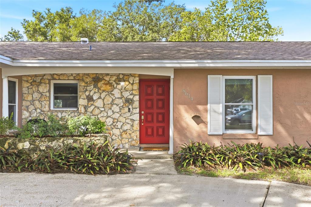 A single-story house exterior features a stone facade, a red front door, and tan stucco — 8614 SANDBERRY BLVD, ORLANDO, FL