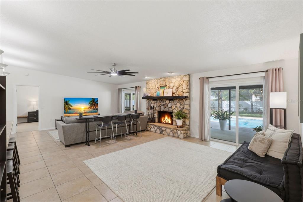 A living room features a stone fireplace, tile flooring, a sofa, and sliding glass doors — 8614 SANDBERRY BLVD, ORLANDO, FL