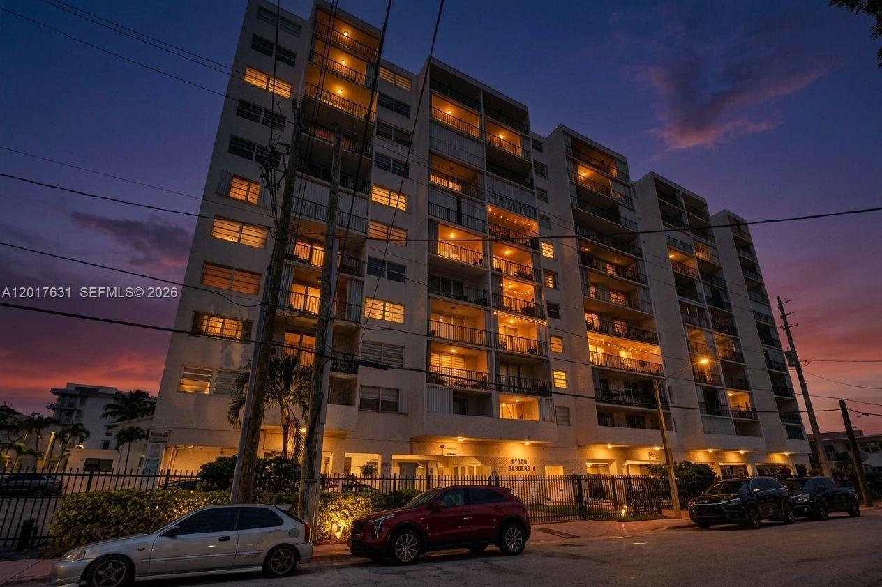 A multi-story residential apartment building is shown at dusk with a parking area in front — 7850 Byron Ave # 702, Miami Beach FL 33141, MIAMI BEACH, FL