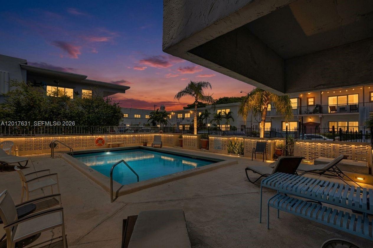 A swimming pool is surrounded by lounge chairs and a concrete deck at sunset — 7850 Byron Ave # 702, Miami Beach FL 33141, MIAMI BEACH, FL