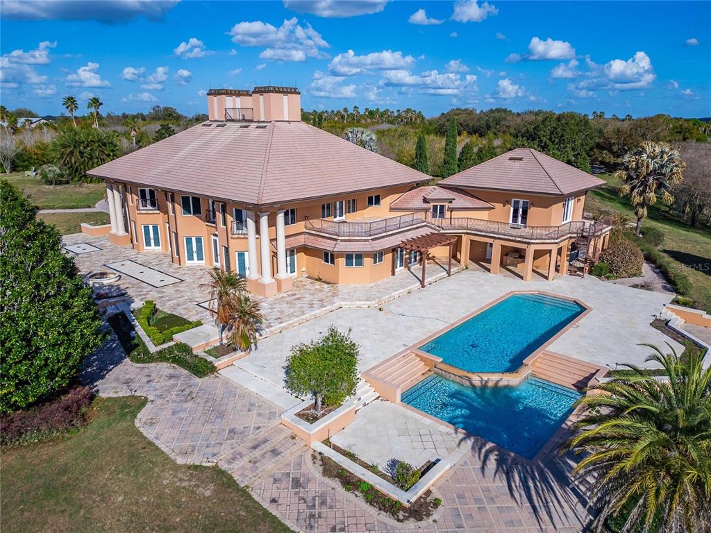 An aerial view of a large, multi-story peach-colored house with a pool and patio — 501 ADAMS BARN ROAD, AUBURNDALE, FL