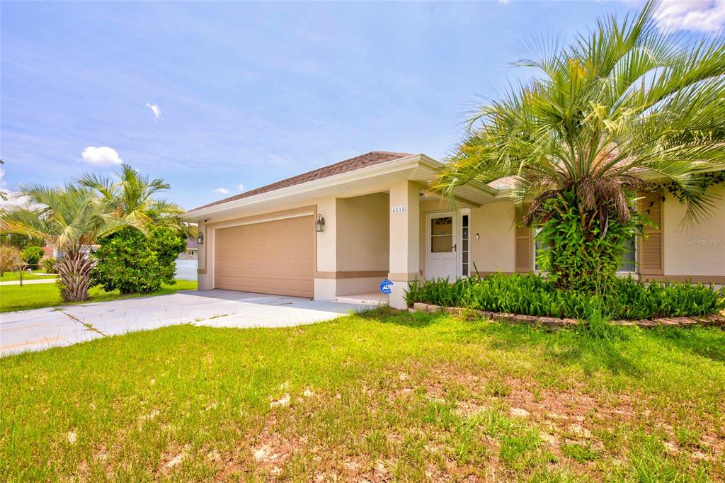 A single-story house with a tan exterior, a two-car garage, and a large palm tree — 4818 SW 114TH STREET, OCALA, FL