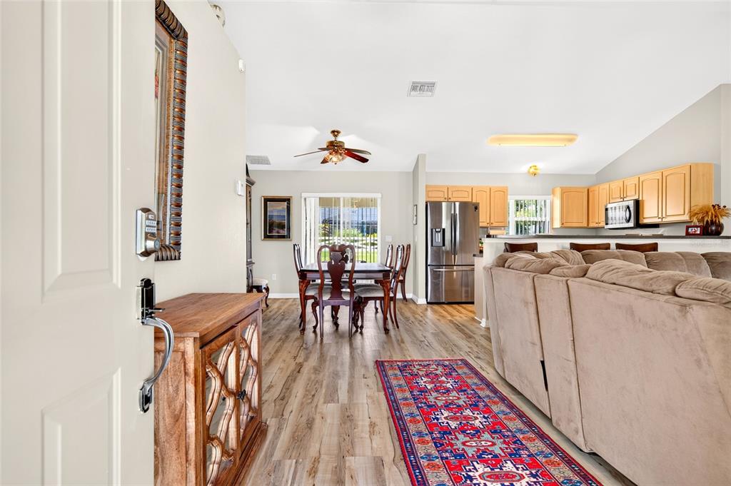 An open-concept living area features wood-look flooring, a dining set, and a kitchen with cabinets — 4818 SW 114TH STREET, OCALA, FL