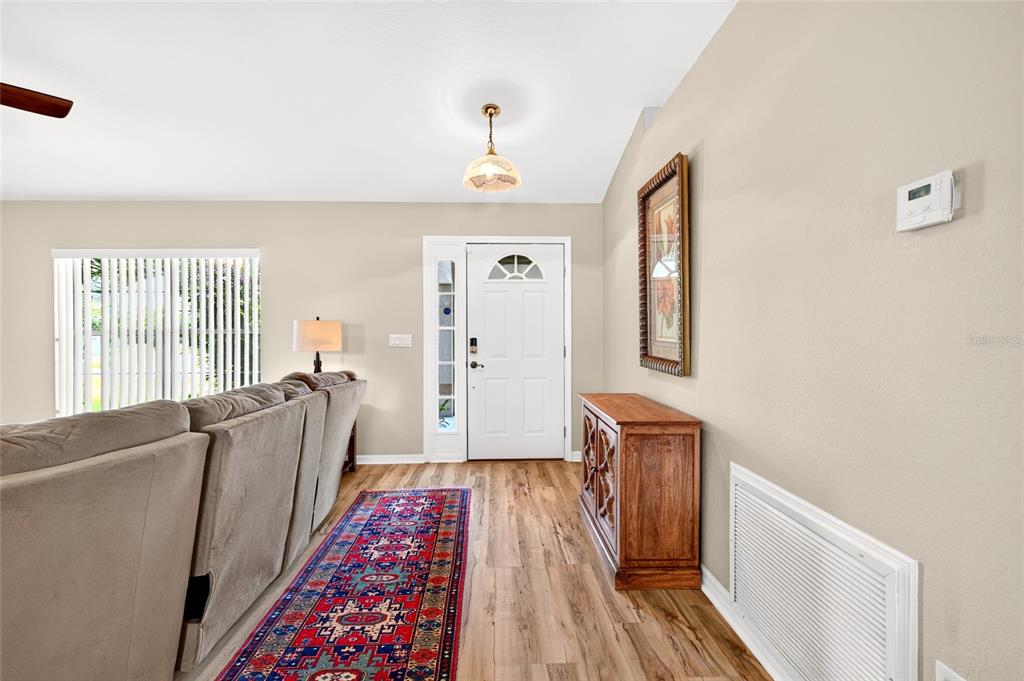 A living room features a beige sofa, a patterned area rug, and a wooden console table — 4818 SW 114TH STREET, OCALA, FL