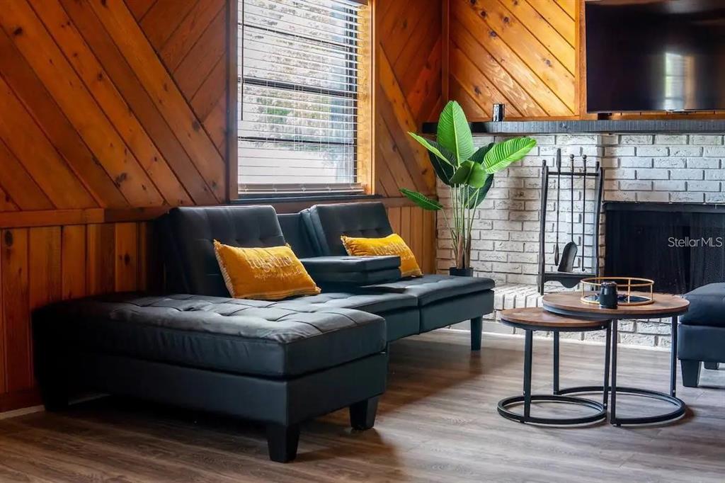 A living room features wood-paneled walls, a white brick fireplace, and a black sectional sofa — 1118 OVERDALE STREET, ORLANDO, FL