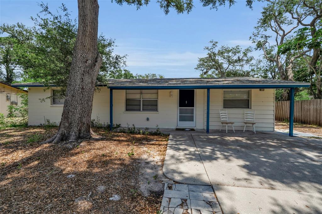 A single-story house with light-colored siding, a covered front porch, and a concrete driveway — 2223 INGRAM AVENUE, SARASOTA, FL