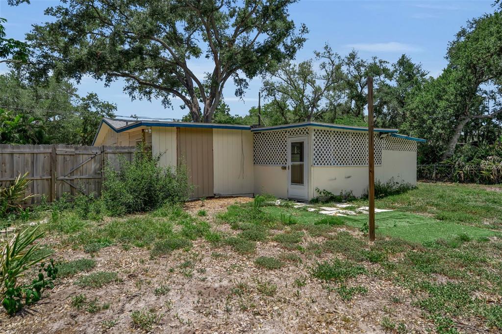 The exterior of a single-story house features light-colored siding, a lattice-covered porch, and a fence — 2223 INGRAM AVENUE, SARASOTA, FL
