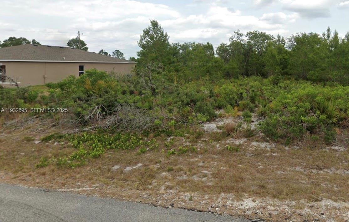 A vacant, overgrown residential lot sits next to a single-story house — 5846 VIRTUDES ST, Sebring FL 33872, SEBRING, FL