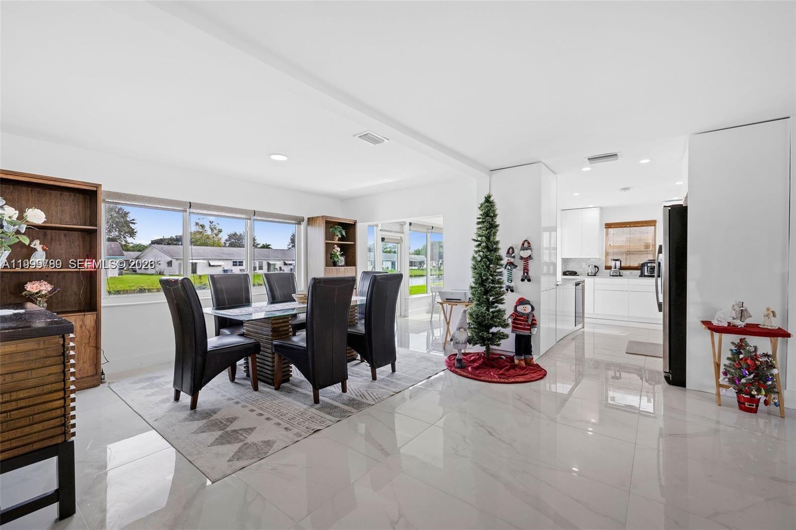 A dining area with a glass table and chairs sits adjacent to a white kitchen — 1086 NW 88th Way, Plantation FL 33322, PLANTATION, FL