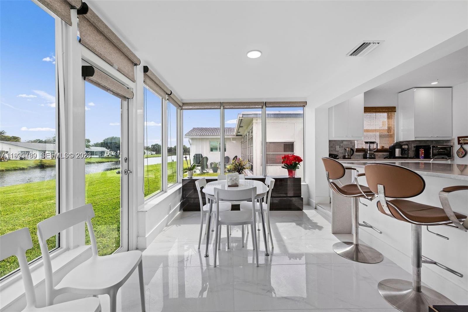 A bright dining area features white tile floors, a round table, and large floor-to-ceiling windows — 1086 NW 88th Way, Plantation FL 33322, PLANTATION, FL