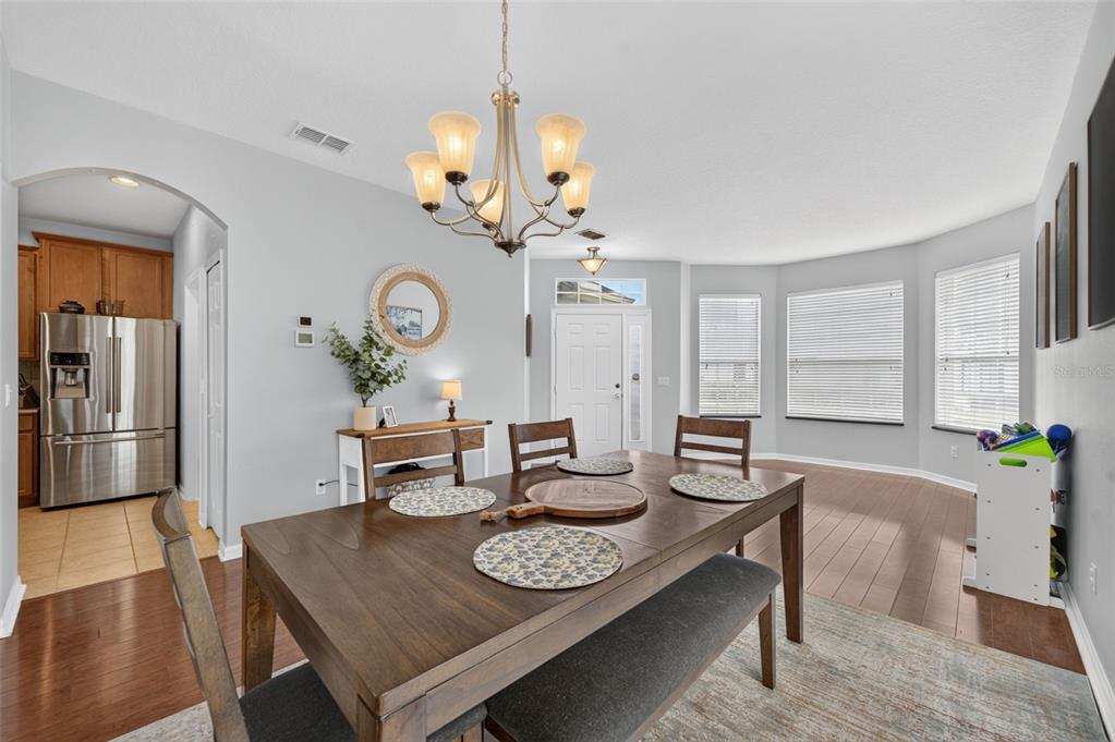 A dining room features a wooden table with a bench, a chandelier, and hardwood floors — 8912 VICKROY TERRACE, OVIEDO, FL