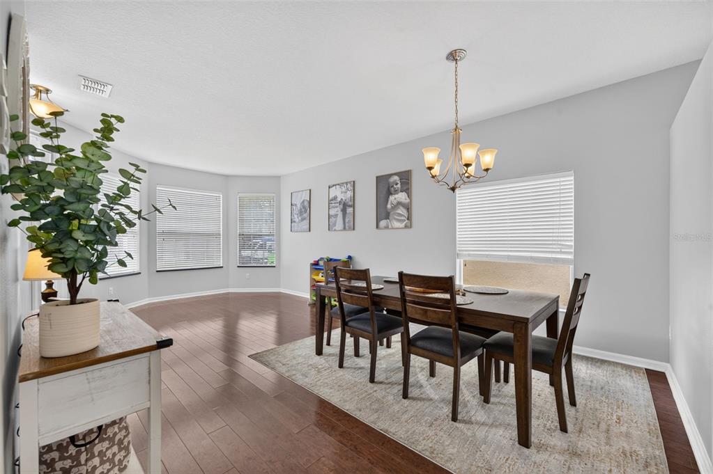 A dining room with a wooden table, chairs, a chandelier, and hardwood floors — 8912 VICKROY TERRACE, OVIEDO, FL