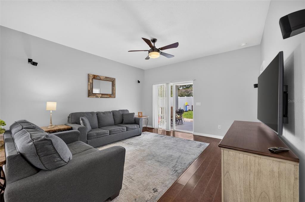 A living room features gray sofas, a large area rug, dark wood floors, and a television — 8912 VICKROY TERRACE, OVIEDO, FL