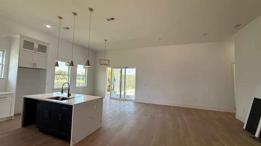 A kitchen with a dark island and white cabinets opens into a spacious living area — 9351 ATHEL DRIVE, PORT CHARLOTTE, FL