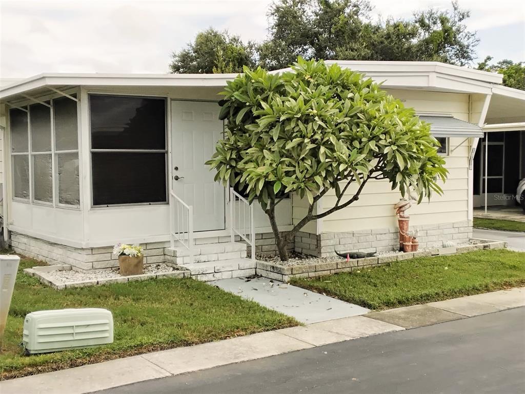 A single-story mobile home with a white exterior, a screened porch, and a large tree — 10118 N LAKE DRIVE UNIT 30, LARGO, FL