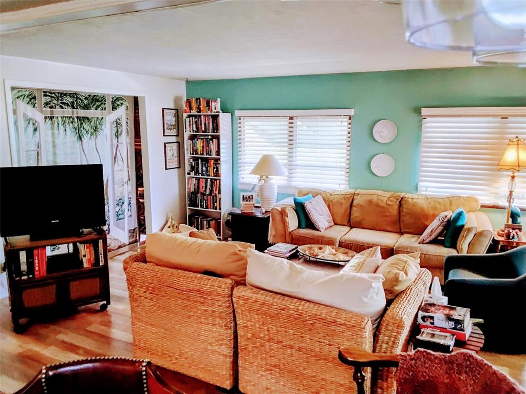 A living room features wicker sofas, a bookshelf, and a television on a wooden stand — 10118 N LAKE DRIVE UNIT 30, LARGO, FL