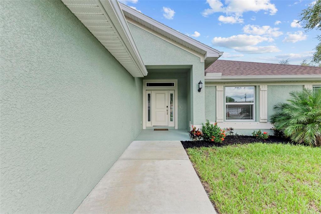 The exterior of a light green house features a concrete walkway leading to the front door — 105 DARTMOUTH ROAD, VENICE, FL