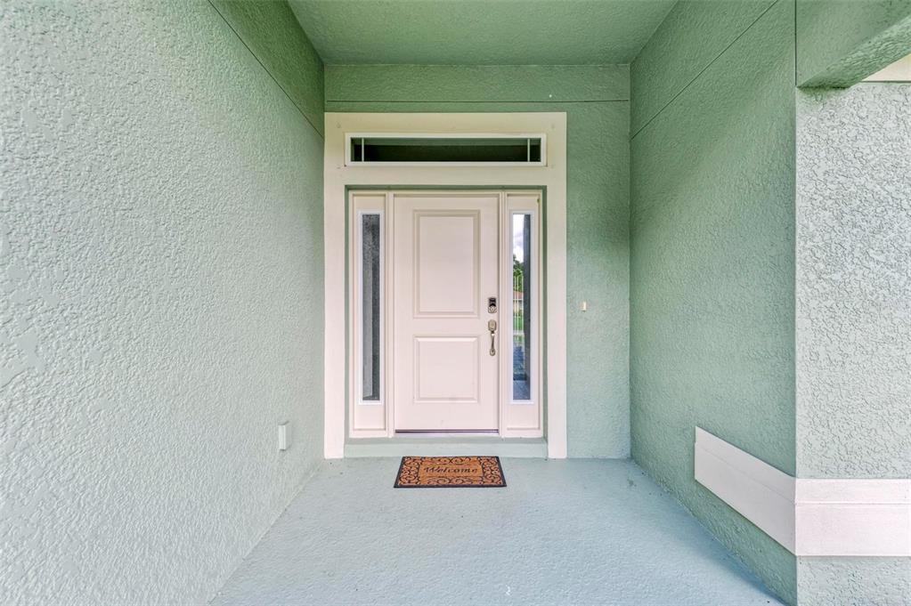 A light green covered entryway features a white front door with side lights and a transom — 105 DARTMOUTH ROAD, VENICE, FL