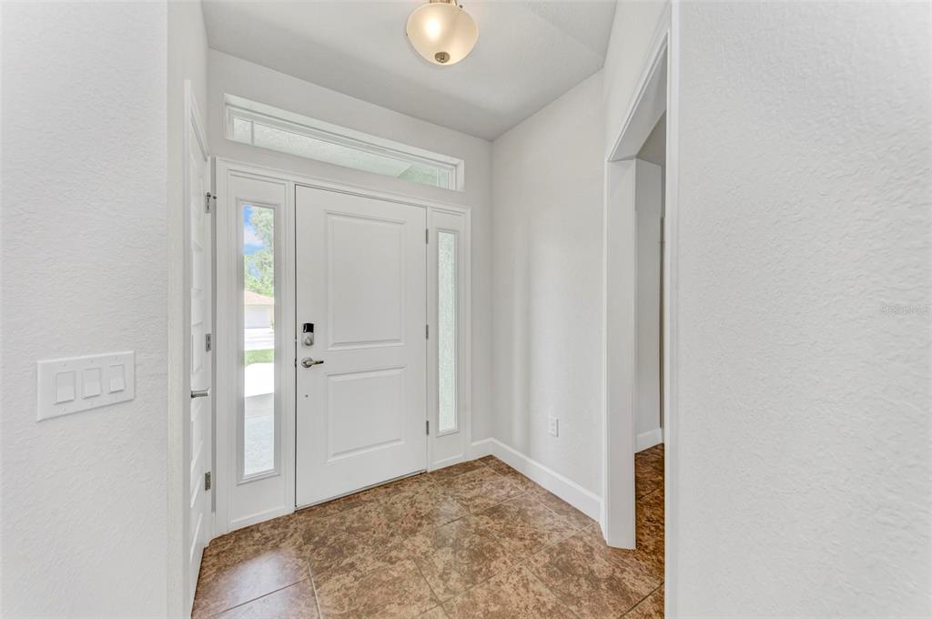 A bright entryway features a white front door with sidelights, tile flooring, and a light fixture — 105 DARTMOUTH ROAD, VENICE, FL
