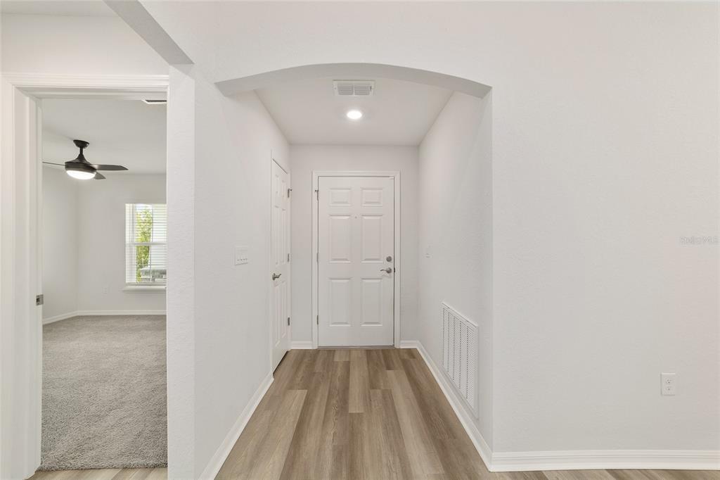 An entryway with wood-look flooring, a white front door, and an arched ceiling transition — 9039 SE 44TH COURT, OCALA, FL