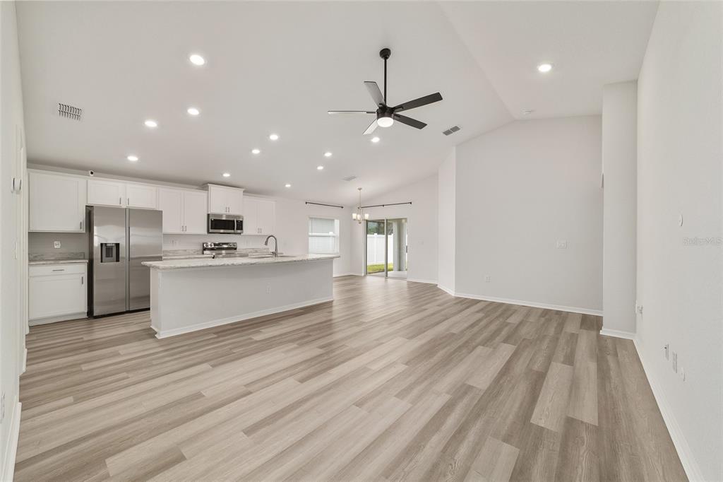 An open-concept kitchen and living area features white cabinetry, stainless steel appliances, and wood-look flooring — 9039 SE 44TH COURT, OCALA, FL