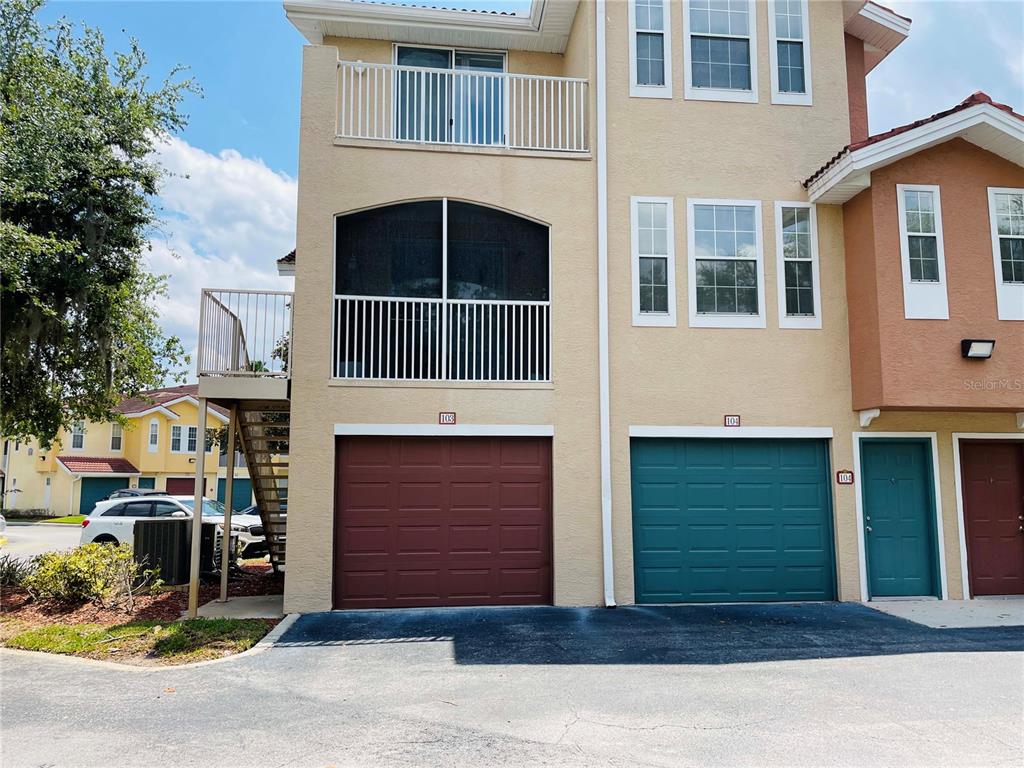 Exterior view of a multi-story townhouse with two garage doors and a screened balcony — 12012 VILLANOVA DRIVE UNIT 103, ORLANDO, FL