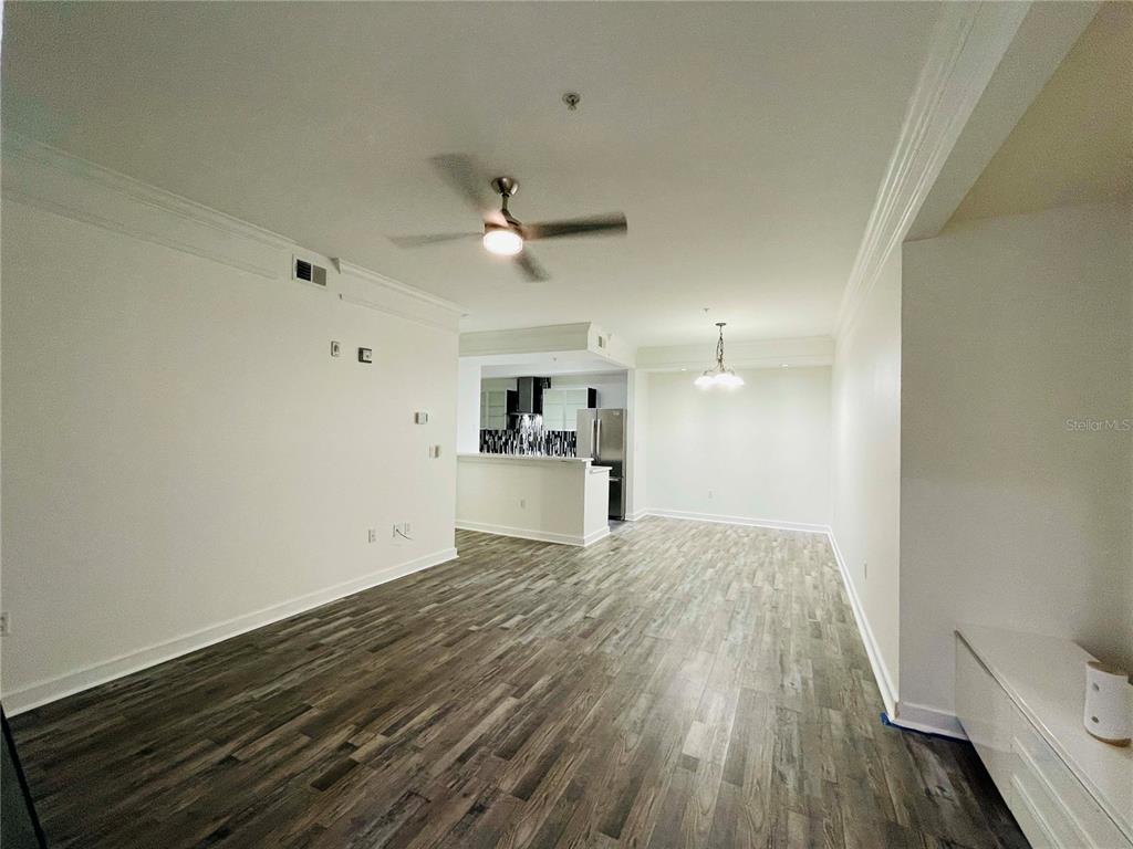 An open-concept living and dining area features wood-look flooring, a ceiling fan, and white walls — 12012 VILLANOVA DRIVE UNIT 103, ORLANDO, FL