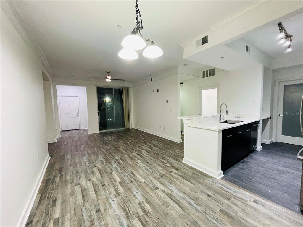 An open-concept living area features wood-look flooring, a kitchen island, and a sliding glass door — 12012 VILLANOVA DRIVE UNIT 103, ORLANDO, FL