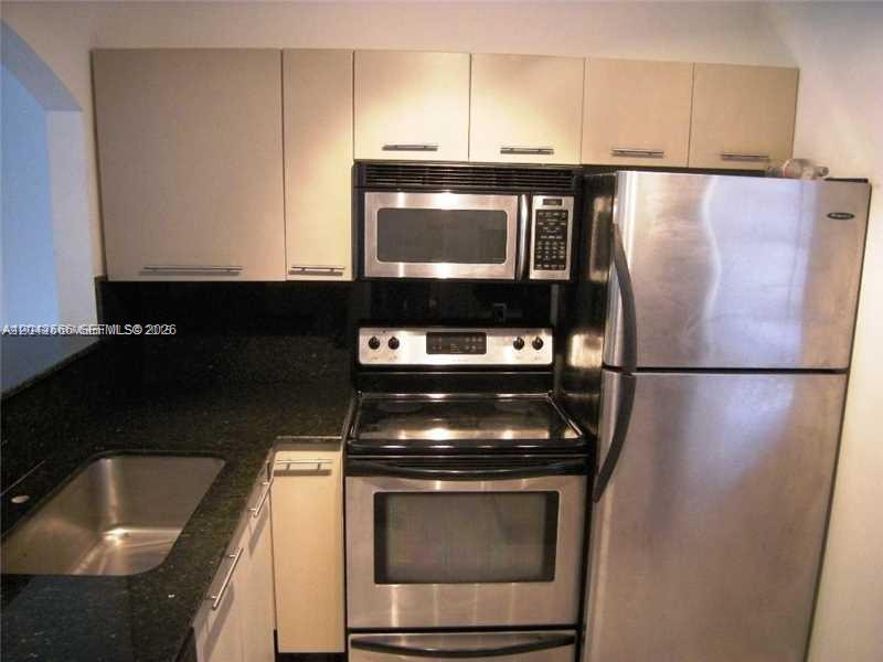 A kitchen features stainless steel appliances, light-colored cabinets, and dark granite countertops — 701 Euclid Ave # 403, Miami Beach FL 33139, MIAMI BEACH, FL