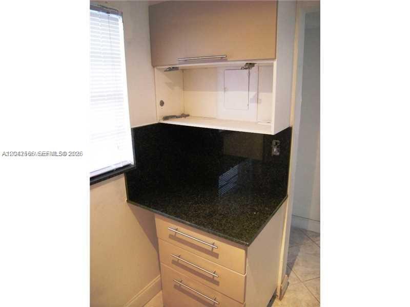 A kitchen area features a dark granite countertop, light-colored cabinets, and a wall-mounted electrical panel — 701 Euclid Ave # 403, Miami Beach FL 33139, MIAMI BEACH, FL