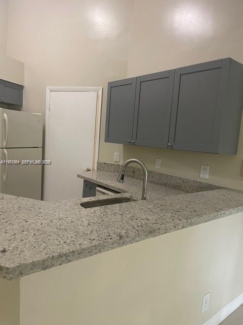 A kitchen features gray cabinets, granite countertops, a stainless steel sink, and a white refrigerator — 9999 Summerbreeze Dr # 1105, Sunrise FL 33322, SUNRISE, FL