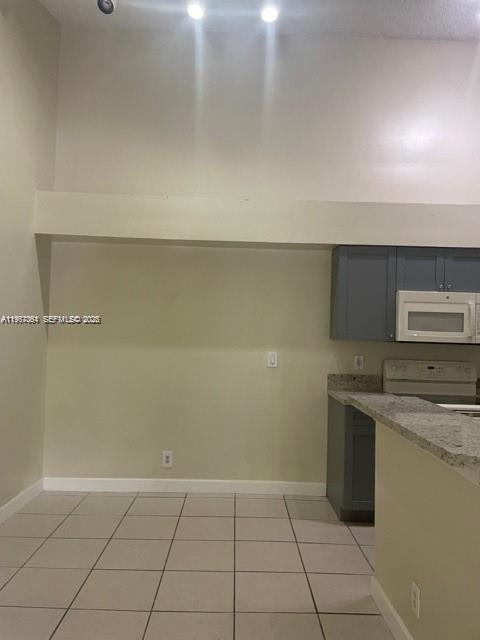 A kitchen area features gray cabinets, a white microwave, and a light-colored tiled floor — 9999 Summerbreeze Dr # 1105, Sunrise FL 33322, SUNRISE, FL
