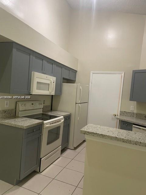 A kitchen features gray cabinets, a white stove, a white refrigerator, and granite countertops — 9999 Summerbreeze Dr # 1105, Sunrise FL 33322, SUNRISE, FL
