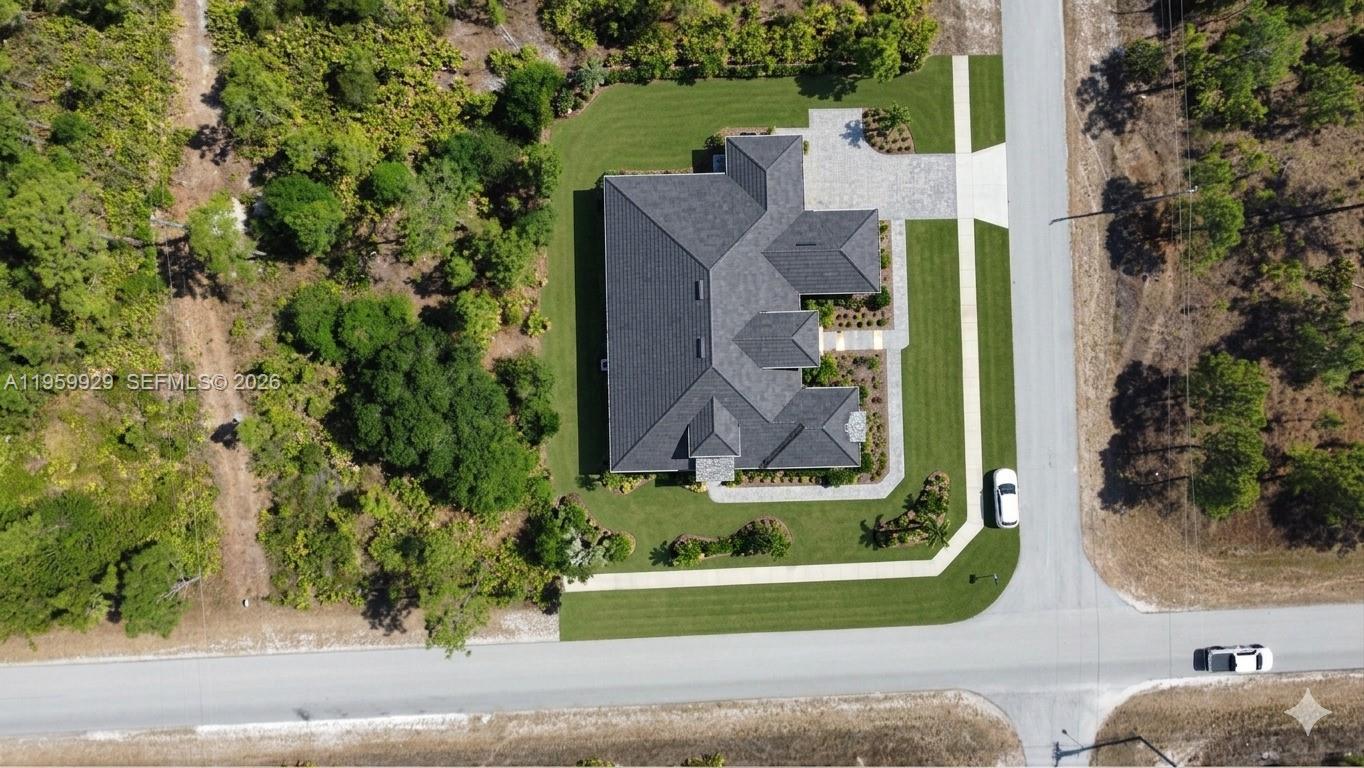 An aerial view shows a house with a dark roof surrounded by lawn and trees — 3007 E 10 St, Lehigh Acres FL 33972, LEHIGH ACRES, FL