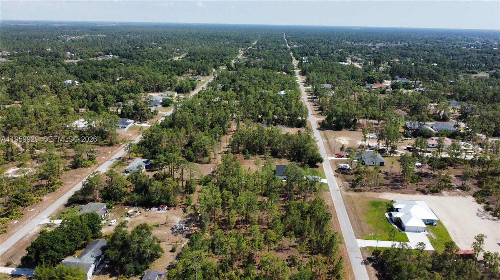 An aerial view shows houses scattered among dense trees along two intersecting paved roads — 3007 E 10 St, Lehigh Acres FL 33972, LEHIGH ACRES, FL