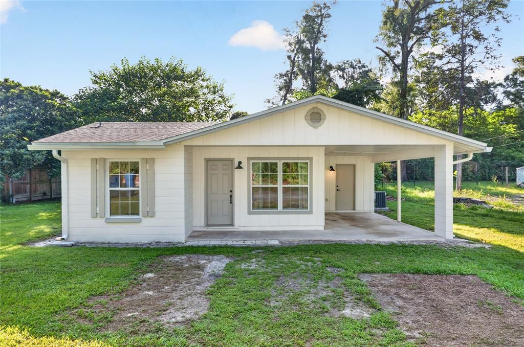 A single-story house with white siding, a front porch, a carport, and a grassy yard — 641 NW 258TH STREET, NEWBERRY, FL