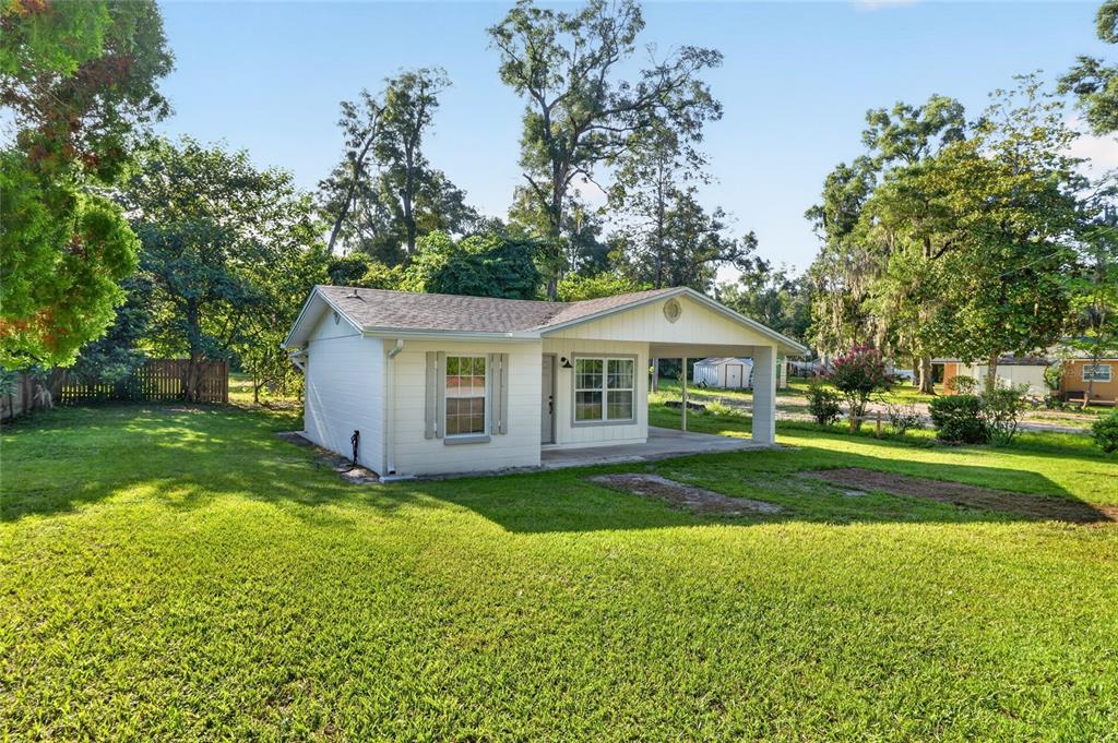 A white single-story house with a covered front porch sits on a large grassy lot — 641 NW 258TH STREET, NEWBERRY, FL