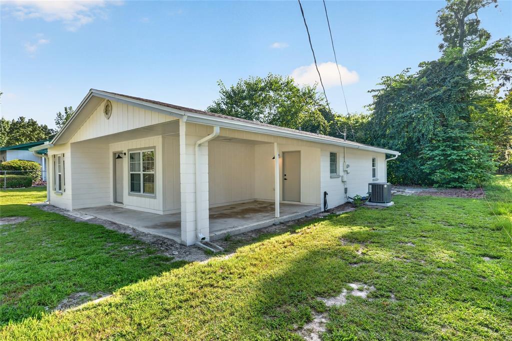 A white house exterior features a covered concrete patio and a side-entry door — 641 NW 258TH STREET, NEWBERRY, FL