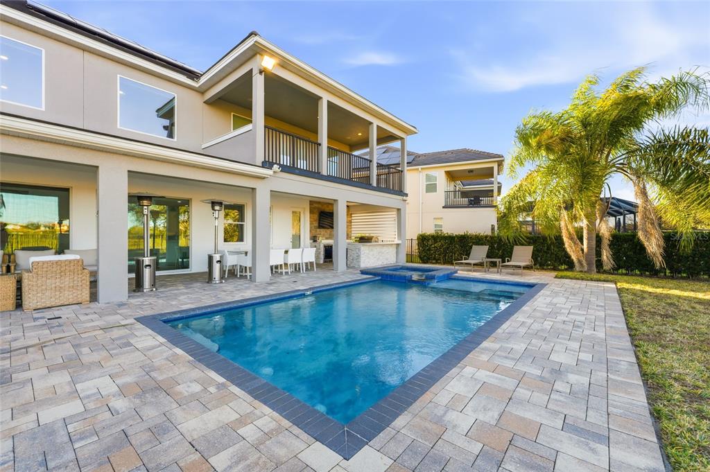 A two-story house exterior features a covered patio, outdoor kitchen, and a rectangular swimming pool — 11545 BRICKYARD POND LANE, WINDERMERE, FL