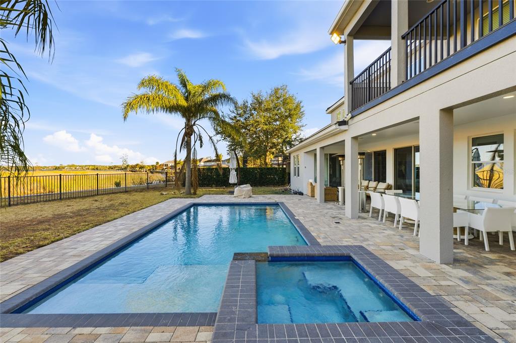 A backyard features a rectangular swimming pool, a hot tub, and a covered patio area — 11545 BRICKYARD POND LANE, WINDERMERE, FL