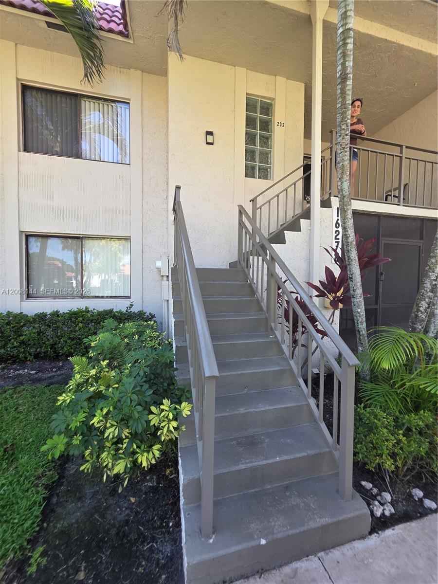 An exterior view shows a concrete staircase leading to a second-floor balcony and unit entrance — 16278 Laurel Dr # 202, Weston FL 33326, WESTON, FL