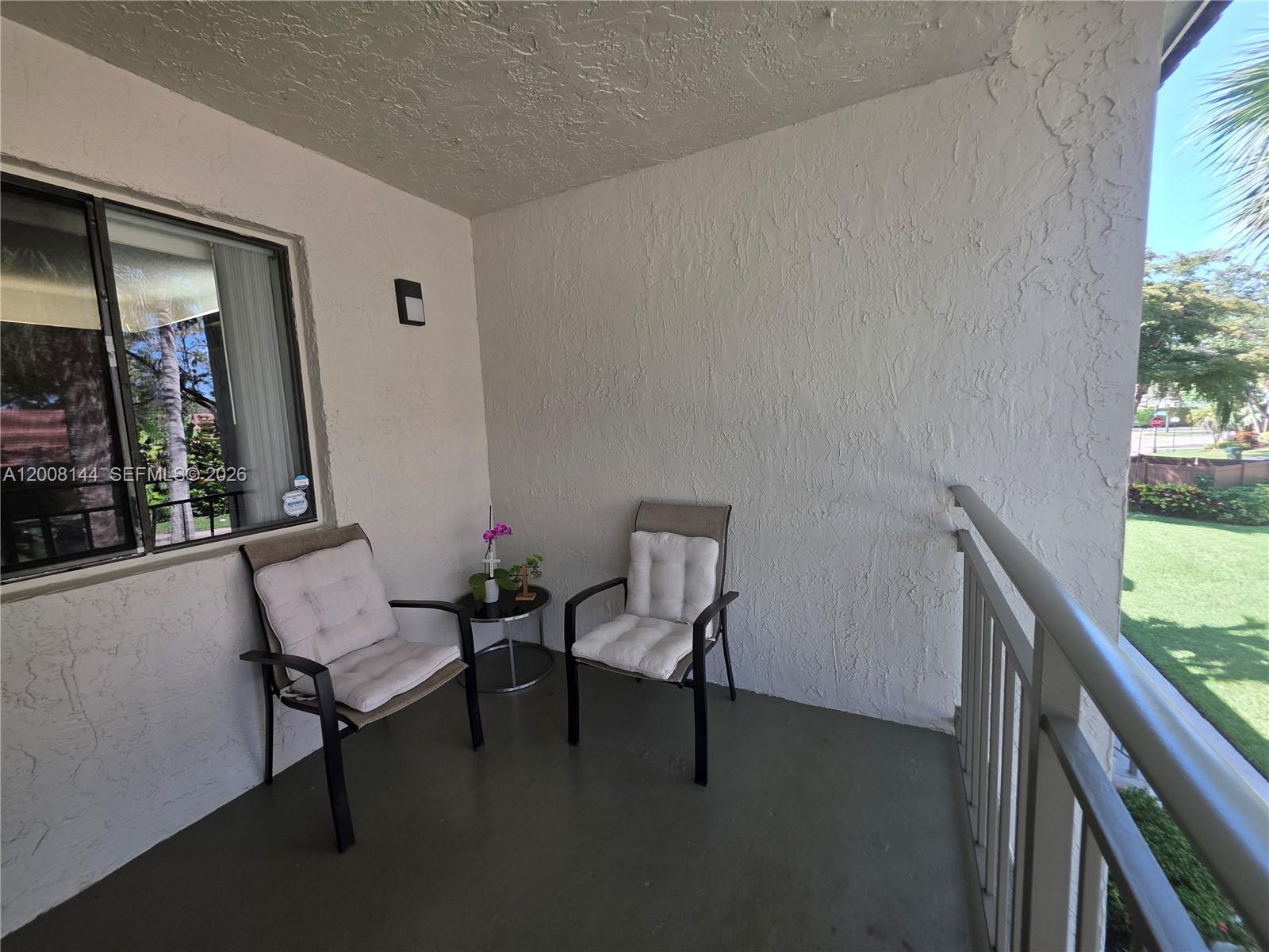 A covered balcony features two chairs, a small side table, and a metal railing — 16278 Laurel Dr # 202, Weston FL 33326, WESTON, FL