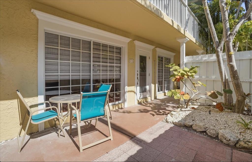 A patio features a small table with two blue chairs and a white fence — 1325 GULF DRIVE N UNIT 125, BRADENTON BEACH, FL