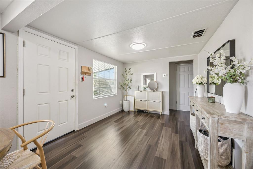 A bright entryway features wood-look flooring, a white front door, and a wooden console table — 5212 ALOHA STREET, ORLANDO, FL