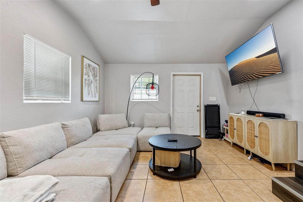 A living room features a large sectional sofa, a round coffee table, and wall-mounted television — 5212 ALOHA STREET, ORLANDO, FL