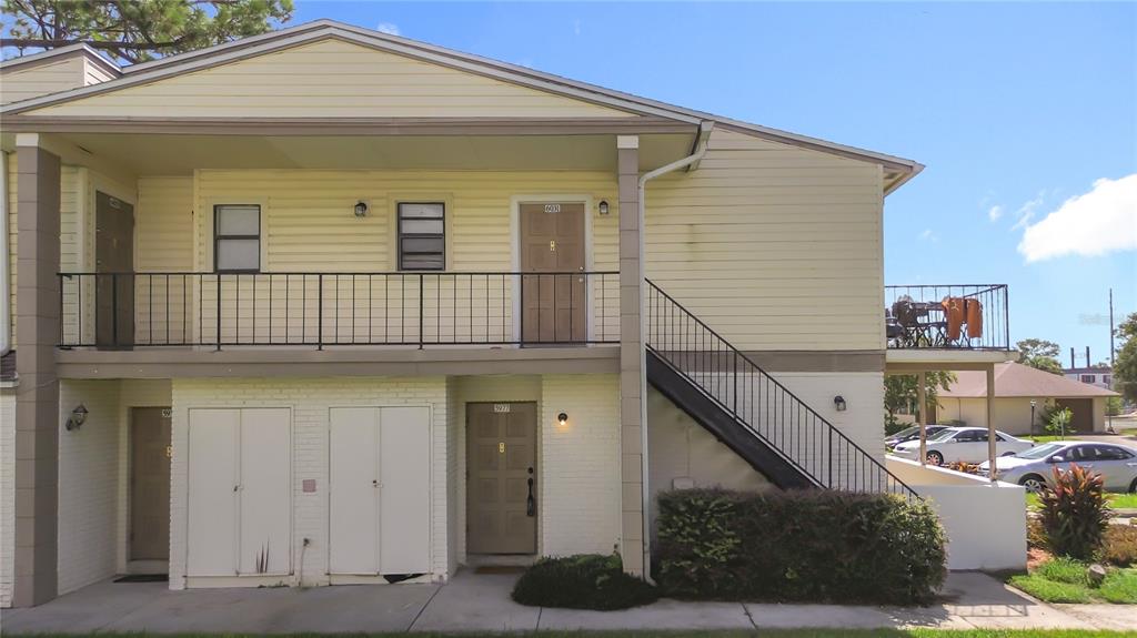 A two-story apartment building with yellow siding, a metal staircase, and a second-floor balcony — 5977 VILLAGE CIRCLE SOUTH UNIT GE, ORLANDO, FL