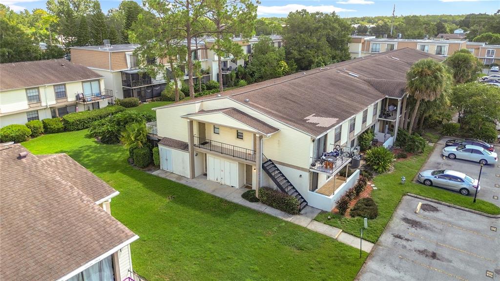 An aerial view shows multi-story apartment buildings with beige siding, brown roofs, and parking lots — 5977 VILLAGE CIRCLE SOUTH UNIT GE, ORLANDO, FL